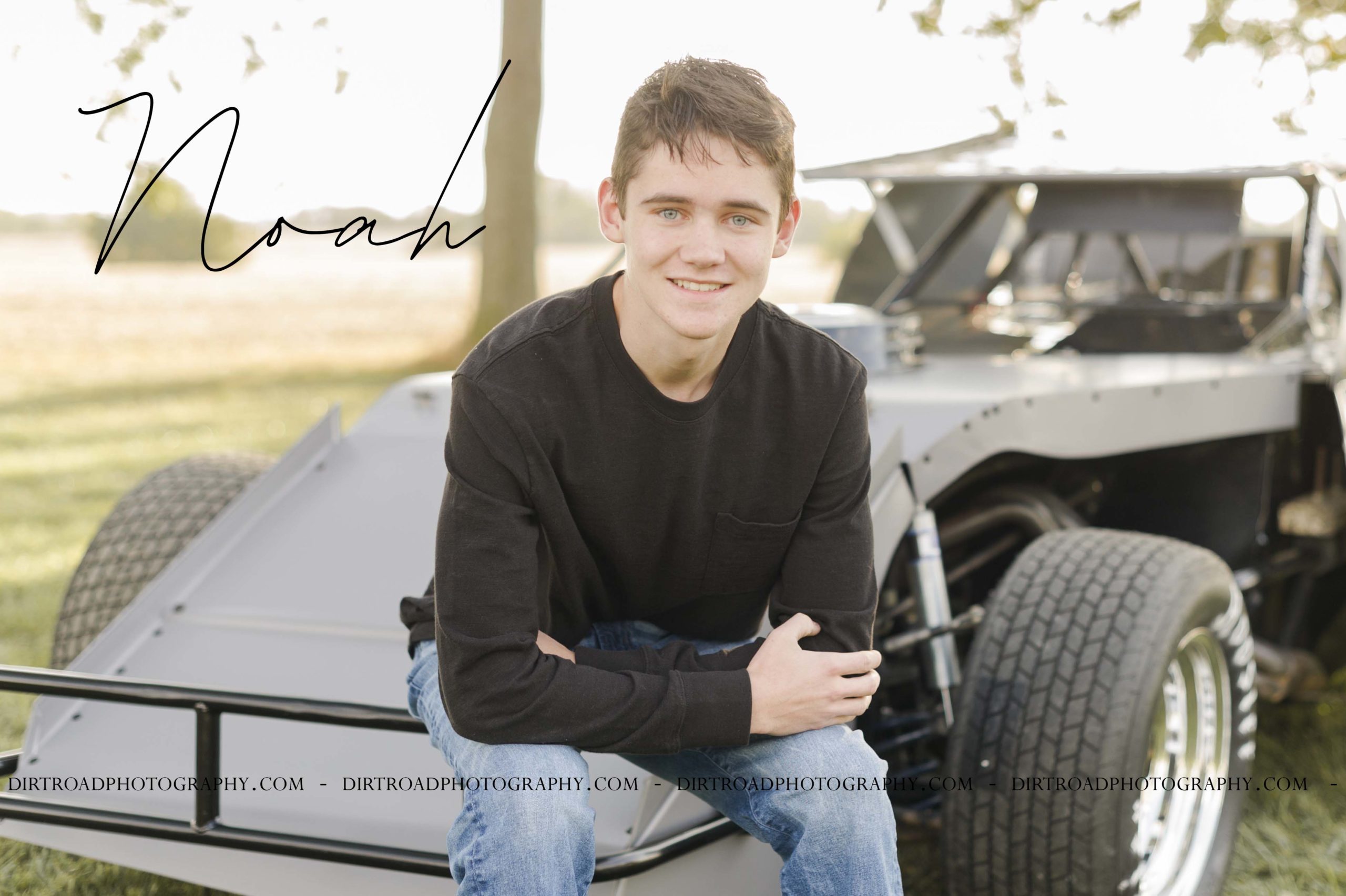 senior pictures of boy sitting with racecar wearing a black long sleeve shirt and jeans. senior pictures of ashland-greenwood high school senior. pictures taken by dirt road photography, lincoln nebraska best senior photographer.