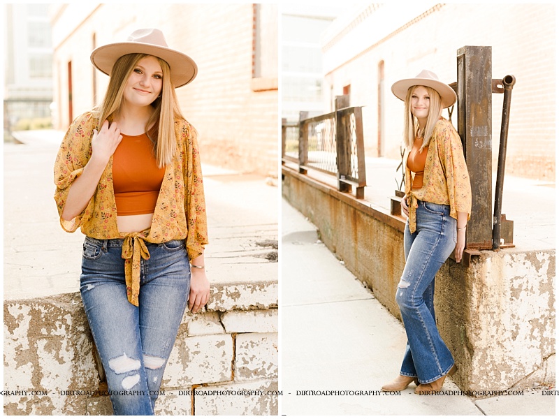 wilber-clatonia high school. picture of senior girl taken near downtown in the haymarket area in lincoln nebraska. urban senior pics standing next to fence and leaning on concrete brick wall. senior picture with girl in jeans, boots and boho top with hat on. picture taken at sunset. nebraska senior photographer located near lincoln, nebraska.