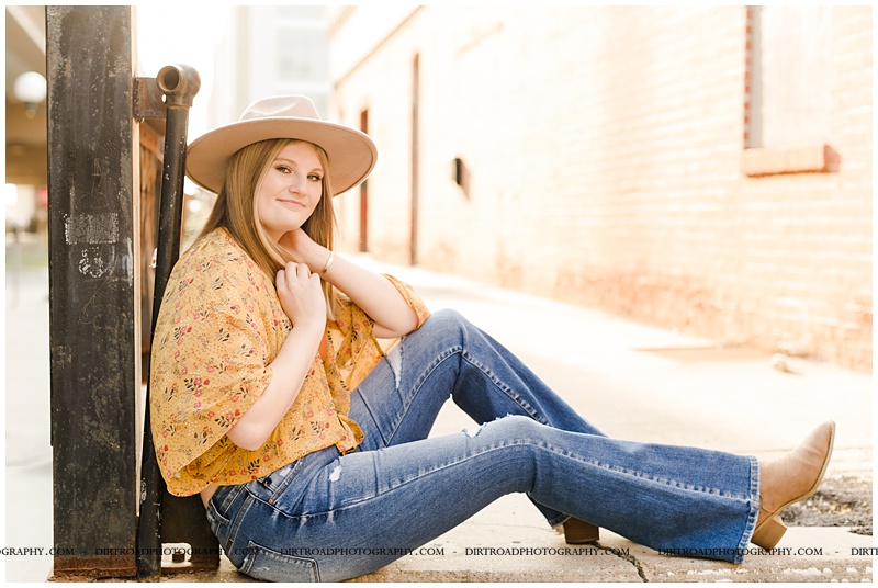 wilber-clatonia high school. picture of senior girl taken near downtown in the haymarket area in lincoln nebraska. senior picture with girl in jeans, boots and boho top with hat on. picture taken at sunset. nebraska senior photographer located near lincoln, nebraska.