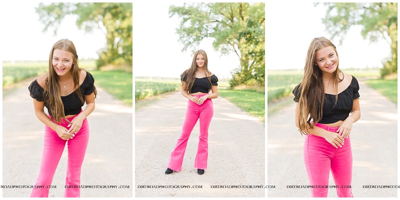 Norris High School near Hickman, Nebraska senior of girl who is standing on a gravel road in the summer with pink bell bottom jeans, a black tied crop top and blakc cowboy hat. nebraska senior photographer located near lincoln, nebraska.