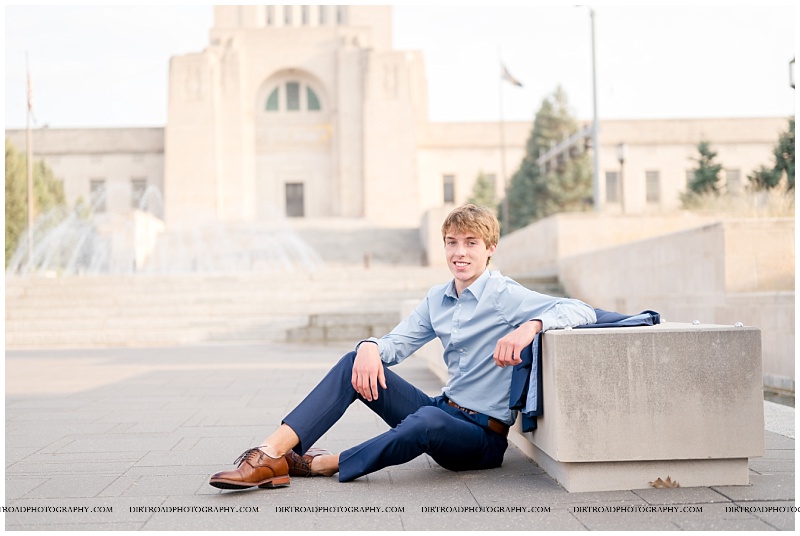 Kaden Boltz wearing a navy suit poses on the steps of the Nebraska State Capitol in Lincoln during his senior photo session.