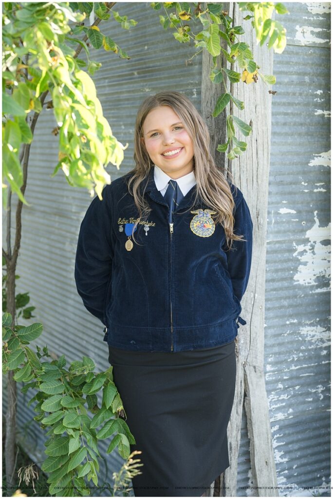 Rural Nebraska senior photos of Waverly senior Esther VanOverbeke in her FFA jacket near farmland and barns.