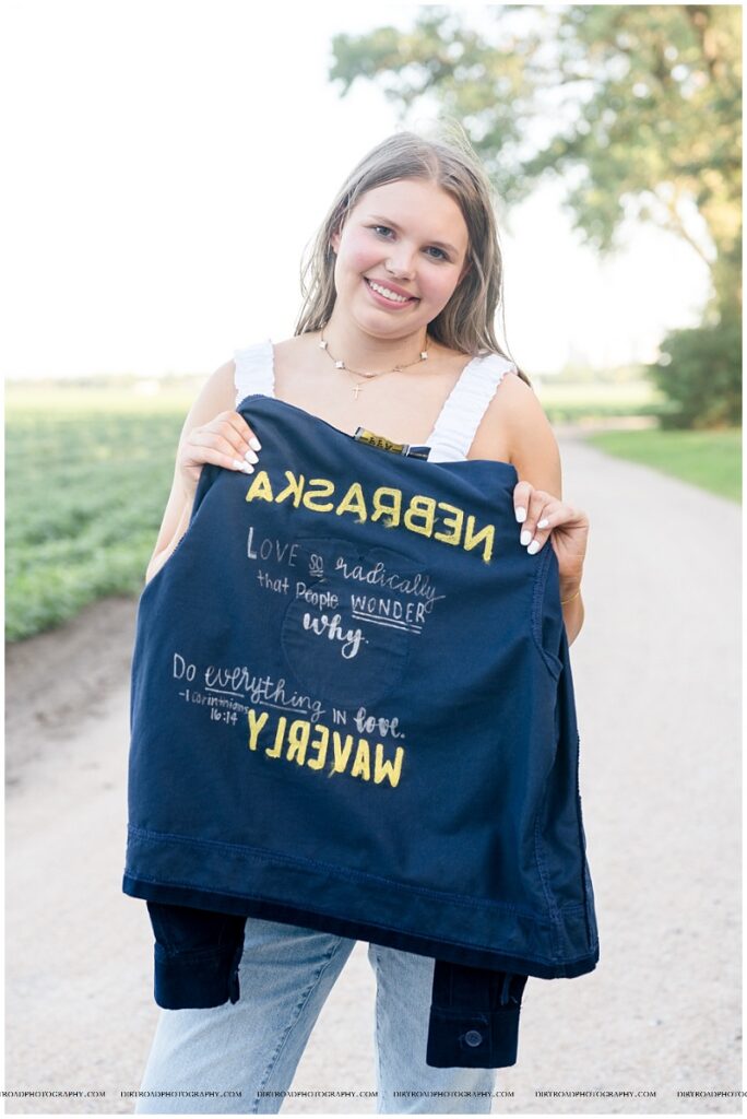 Country senior photos of Waverly senior Esther VanOverbeke walking down a dirt road in her FFA jacket.